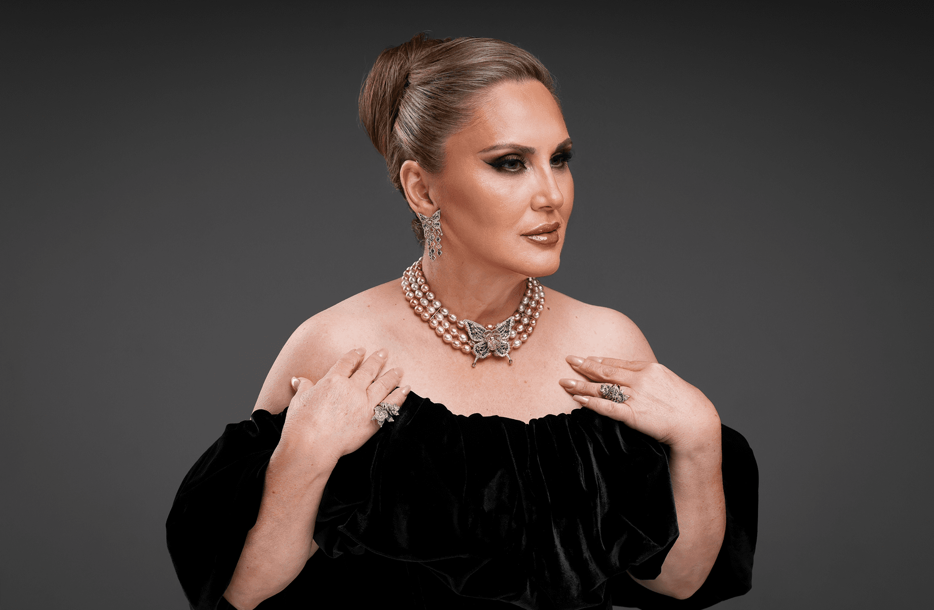 Elegant woman in a black off-shoulder dress with statement jewelry.