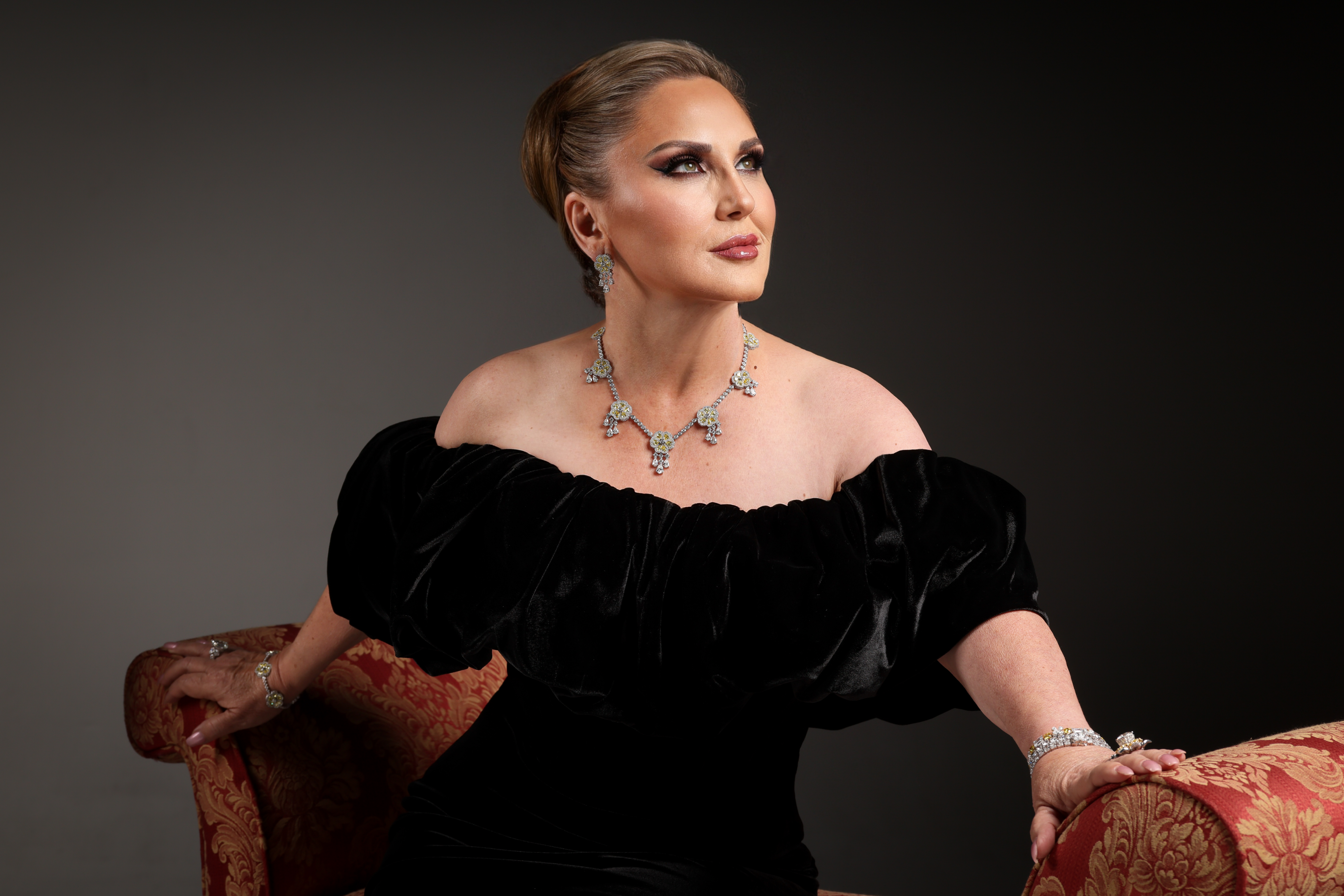 Elegant woman in a black off-shoulder dress adorned with sparkling jewelry.