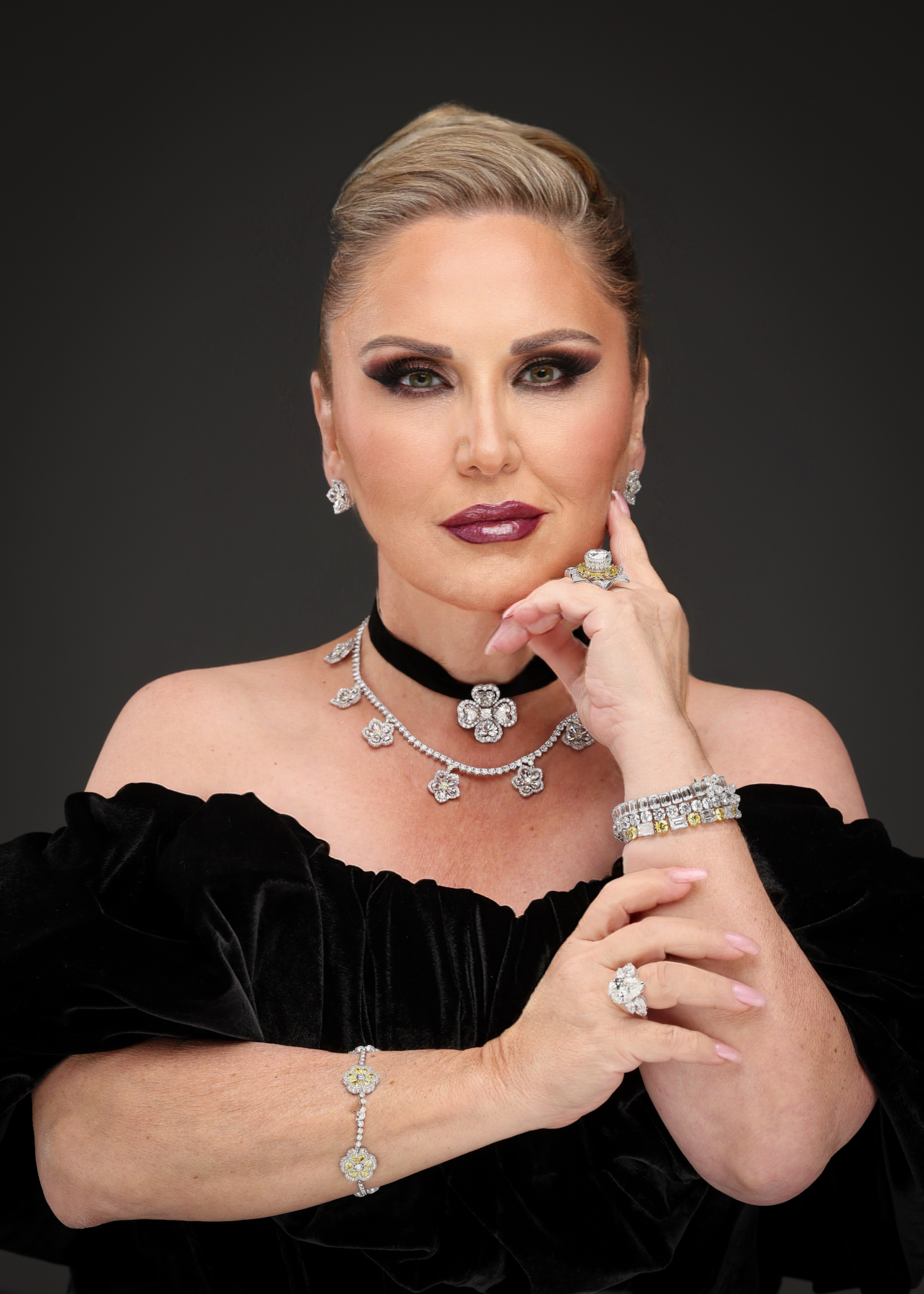 Elegant woman adorned with striking diamond jewelry and a black velvet off-shoulder dress.