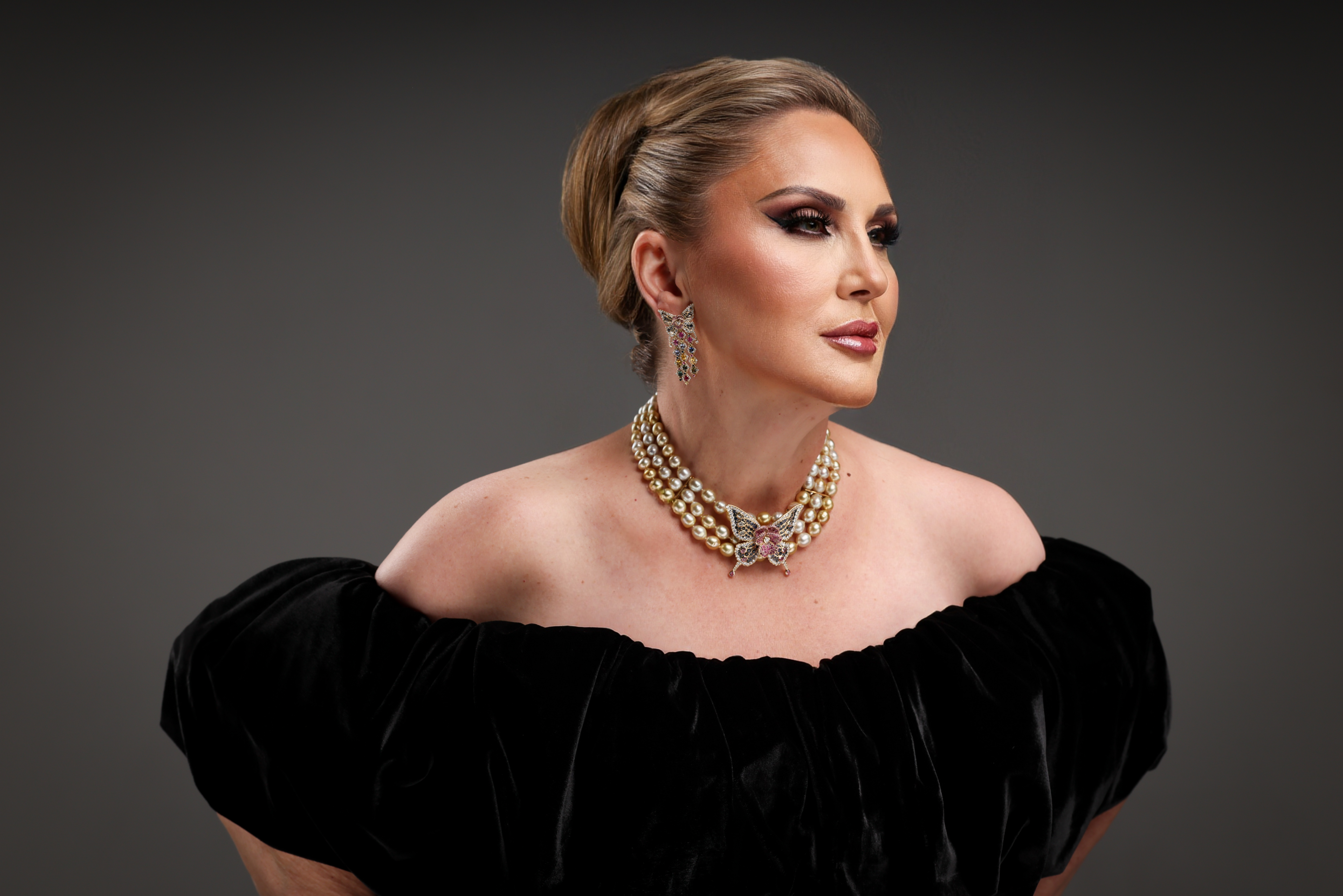 Elegant woman in black velvet with pearl jewelry and dramatic makeup.