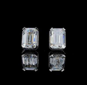 Pair of rectangular diamond earrings with a reflective black backdrop.