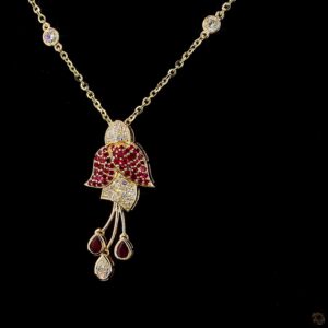 Gold necklace with red gemstone flower pendant.