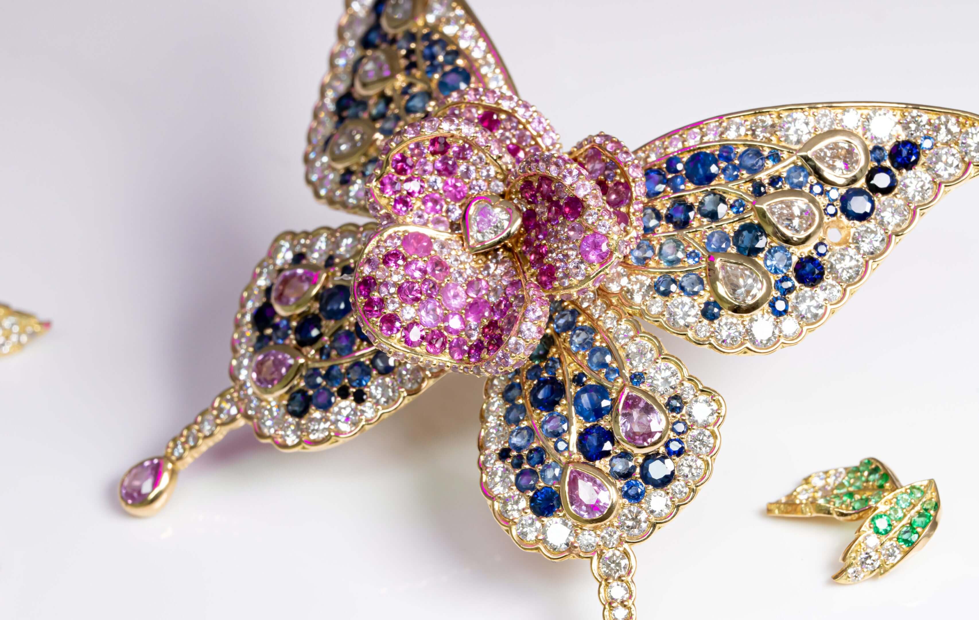 A jeweled butterfly brooch with pink, blue, and gold stones.